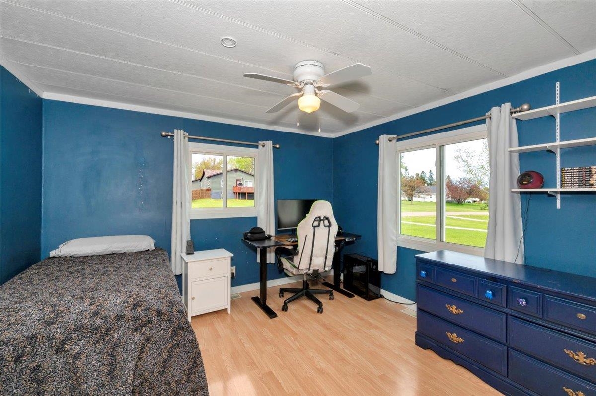 1632 9th Avenue Two Harbors, MN 55616 - Photo 12 of 21 Bedroom with multiple windows, light wood-type flooring, a ceiling fan, and baseboards