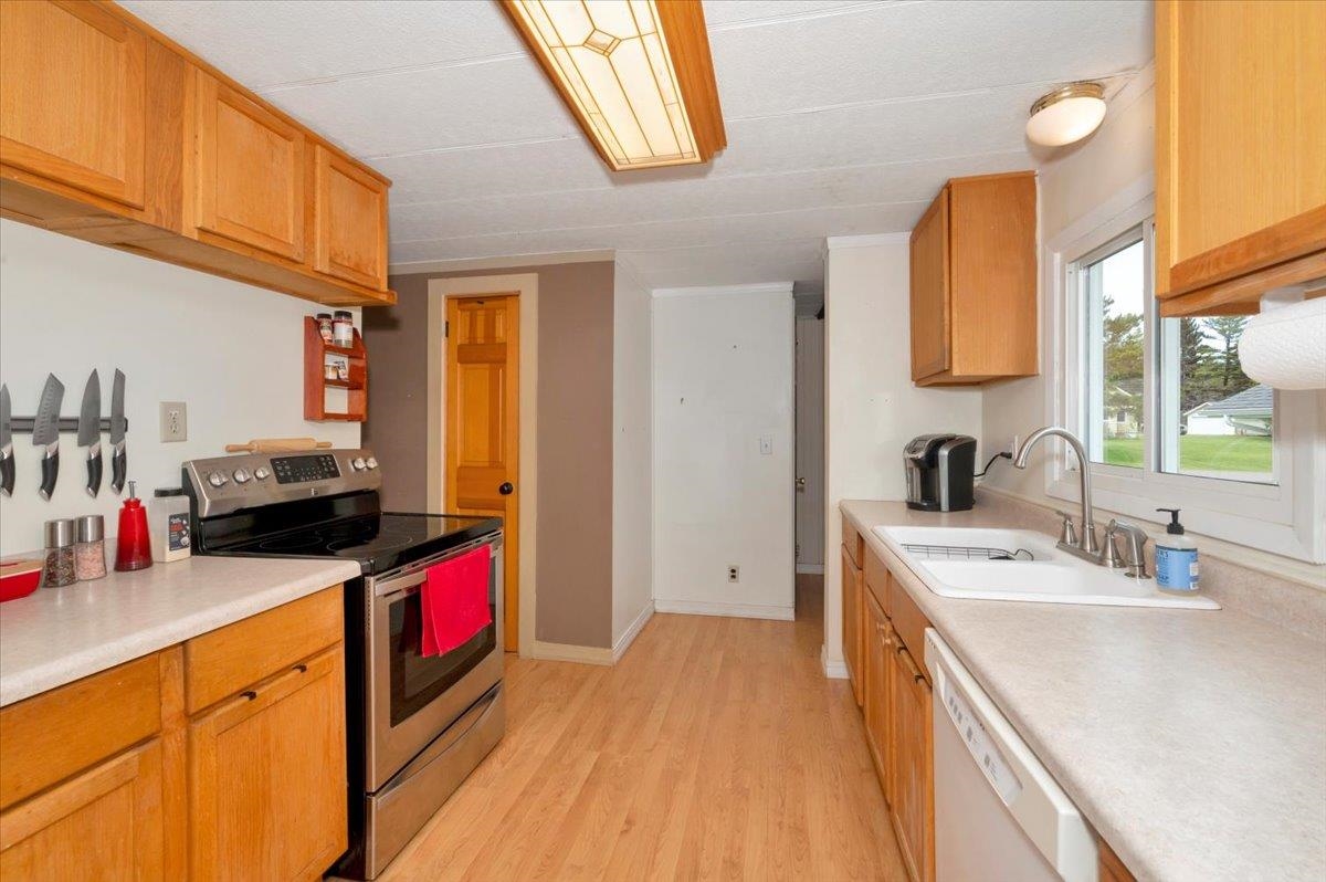 1632 9th Avenue Two Harbors, MN 55616 - Photo 7 of 21 Kitchen featuring stainless steel electric range, dishwasher, light countertops, light wood finished floors, and a sink