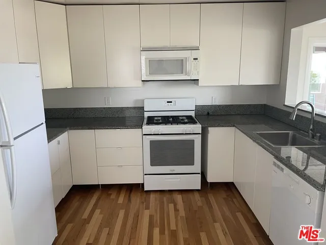 a kitchen with granite countertop white cabinets and white appliances