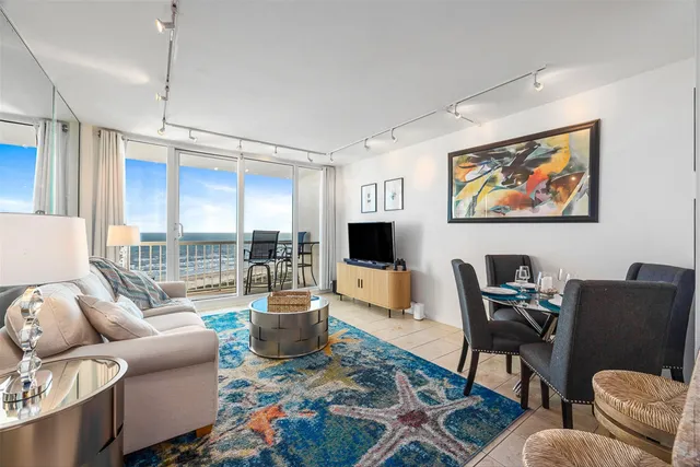 a living room with furniture a flat screen tv and a floor to ceiling window