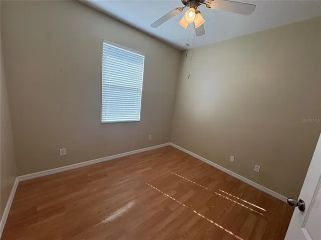 an empty room with a chandelier fan and windows