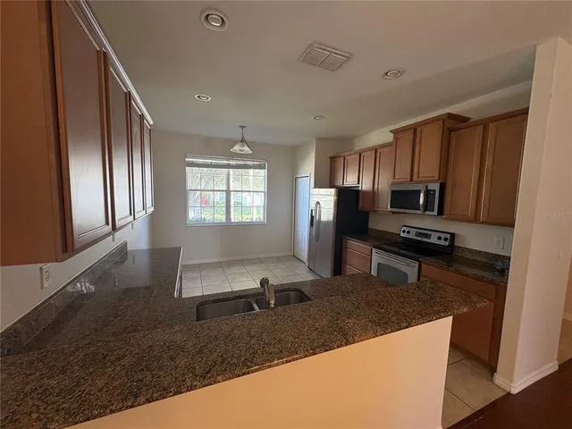 a kitchen with granite countertop a stove refrigerator and microwave
