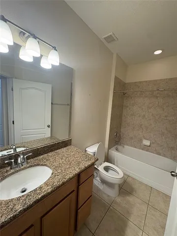 a bathroom with a granite countertop sink a toilet and a large mirror