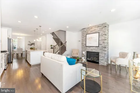 a living room with furniture kitchen view and a wooden floor