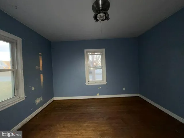 an empty room with wooden floor cabinet and windows