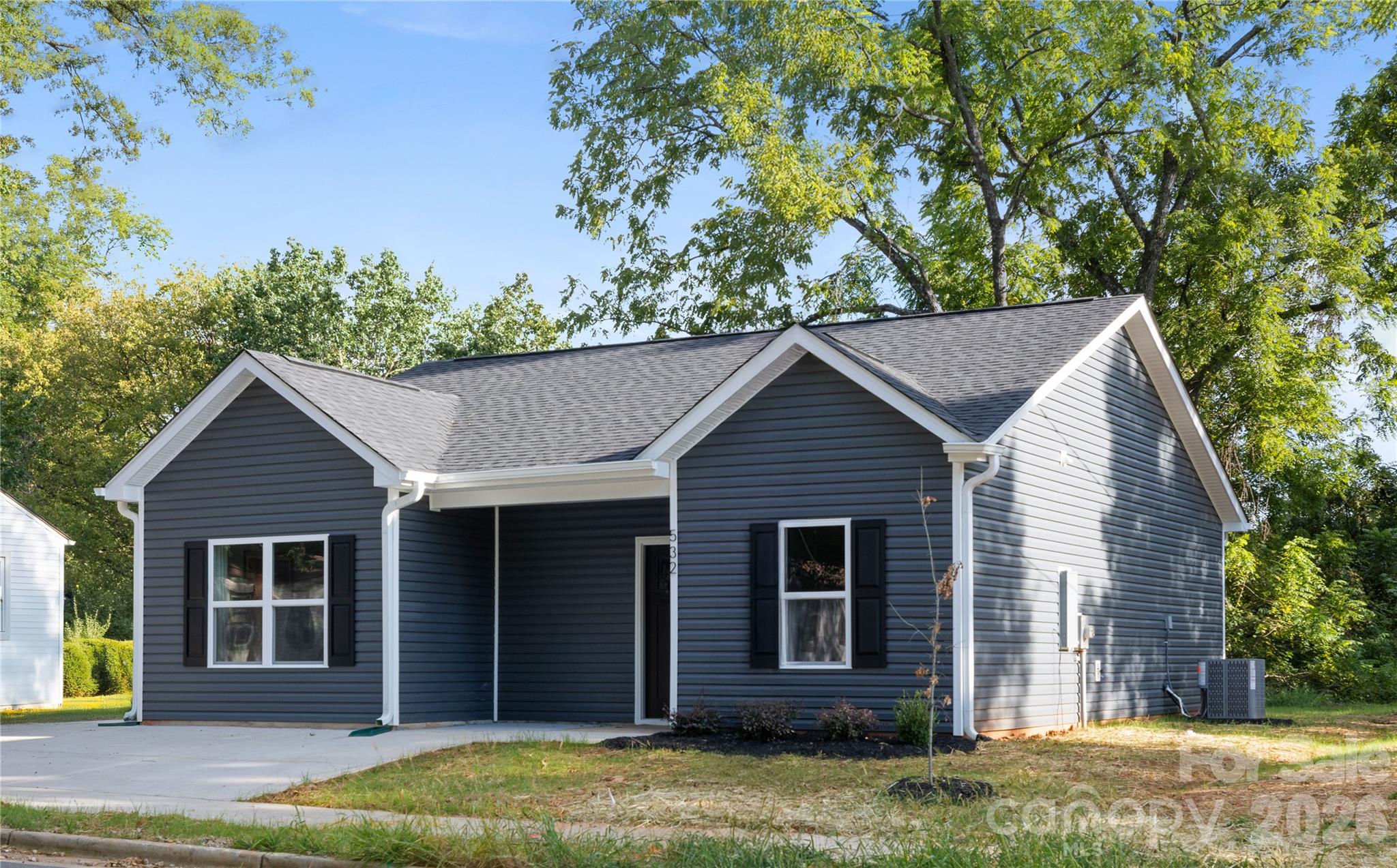 a view of a house with a yard plants and large tree