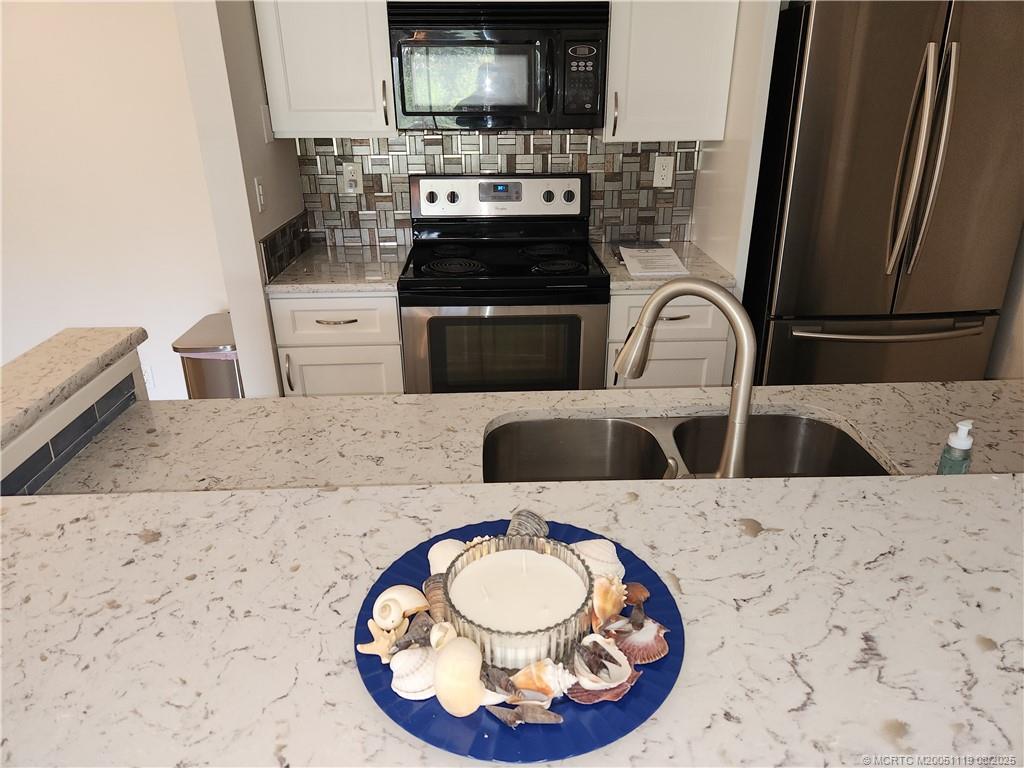 2502 Southeast Anchorage Cove, Unit H2 Port St. Lucie, FL 34952 - Photo 12 of 37 a kitchen with a stove a sink and a microwave
