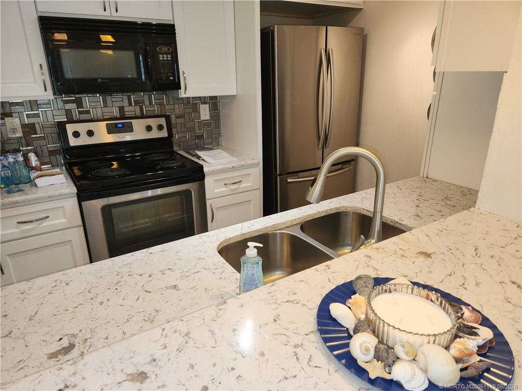2502 Southeast Anchorage Cove, Unit H2 Port St. Lucie, FL 34952 - Photo 13 of 37 a kitchen with stainless steel appliances kitchen island granite countertop a stove a sink and a microwave