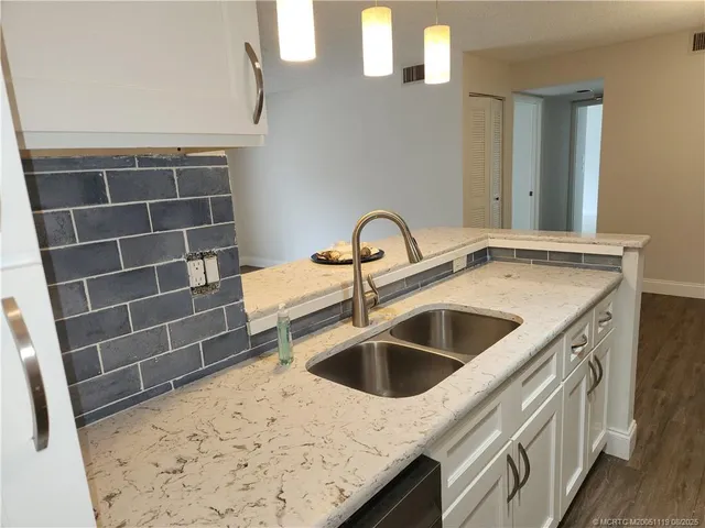 a kitchen with a sink and a stove with wooden floor
