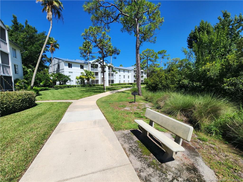 2502 Southeast Anchorage Cove, Unit H2 Port St. Lucie, FL 34952 - Photo 36 of 37 a view of a garden with a bench and a lake view