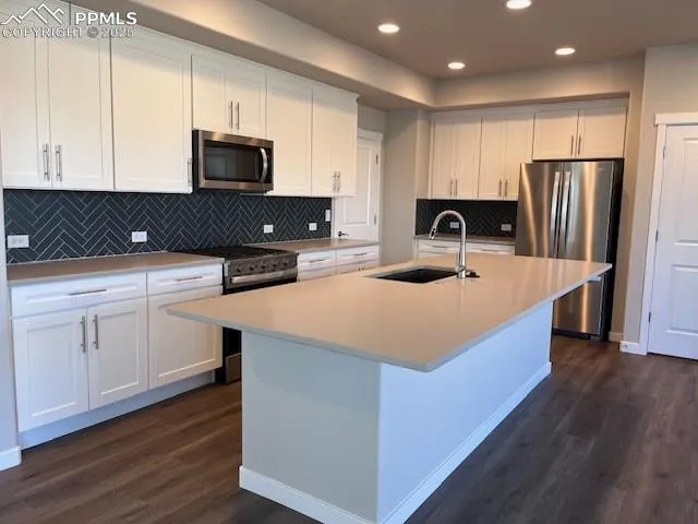 a kitchen with kitchen island a sink a stove a microwave and white cabinets