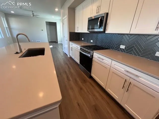 a kitchen with kitchen island a counter top space a sink a stove and a refrigerator