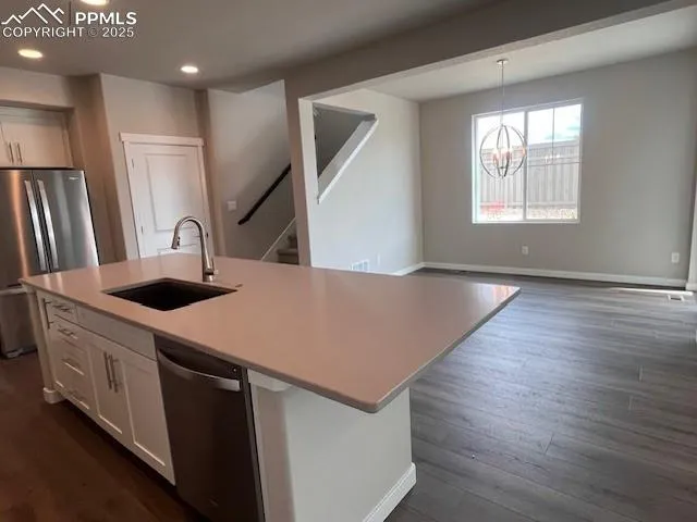 a kitchen with stainless steel appliances a kitchen island hardwood floor sink and wooden floor