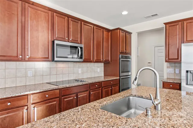 a kitchen with granite countertop a sink cabinets and stainless steel appliances