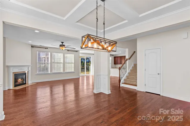 a view of an empty room with wooden floor fireplace and a window