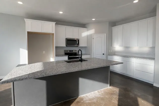 a kitchen with kitchen island a sink stainless steel appliances and cabinets