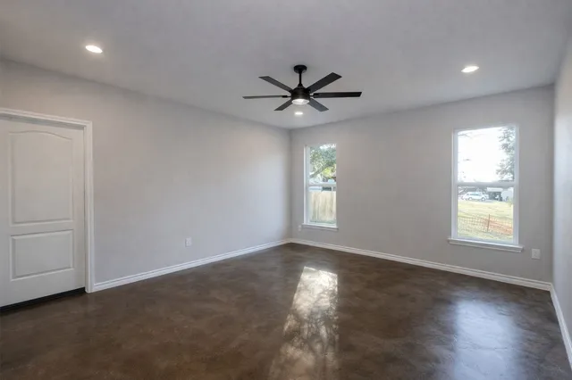 a view of an empty room with a window and wooden floor