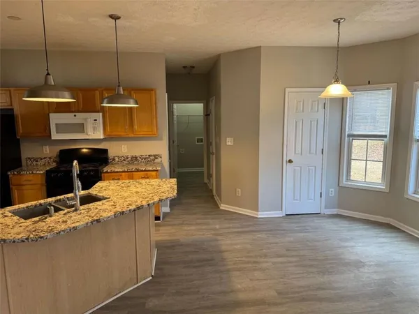 a kitchen with kitchen island a counter top space a sink a window and wooden floor