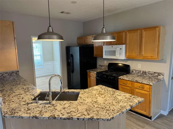 a kitchen with stainless steel appliances granite countertop a stove a refrigerator and a wooden cabinets