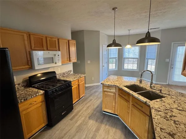 a kitchen that has a sink a stove and a wooden floor