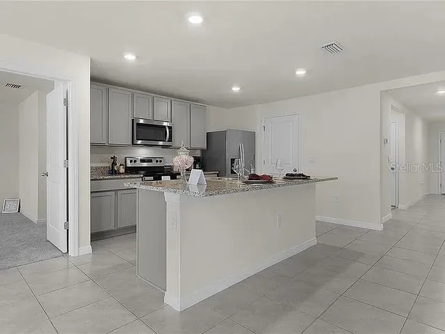 a kitchen with kitchen island a counter top space stainless steel appliances and cabinets