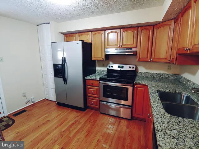 a kitchen with granite countertop wooden floors and stainless steel appliances