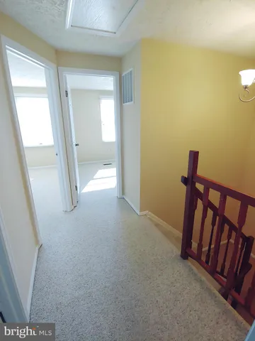 a view of a hallway with wooden floor and a bathroom