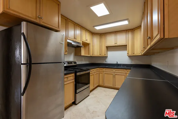 a kitchen with stainless steel appliances granite countertop a refrigerator a stove and a sink
