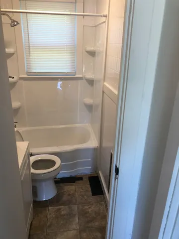 a bathroom with a granite countertop toilet and a tub