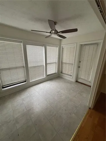 an empty room with chandelier fan and windows