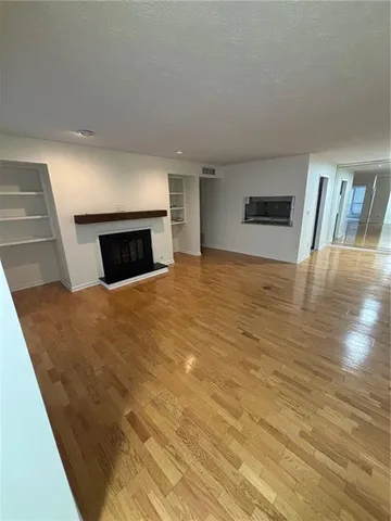 a view of empty room with wooden floor and fireplace