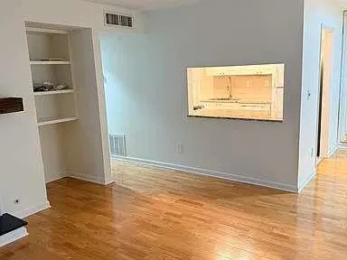 a view of an empty room with wooden floor and a window