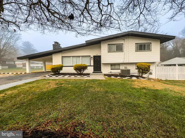 a backyard of a house with table and chairs under an umbrella