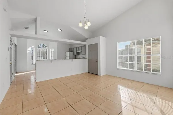 a view of an empty room with kitchen and window