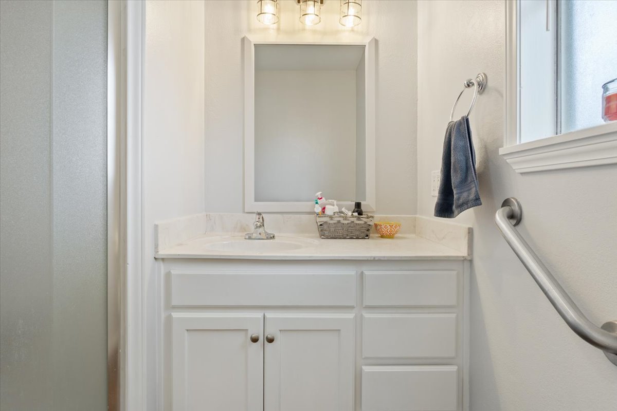 1607 North Harding Avenue Cameron, TX 76520 - Photo 19 of 37 White vanity with integrated sink and mirror provides a clean and functional bathroom space.