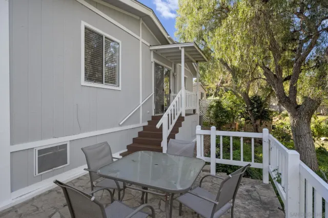 a front view of a house with wooden deck and furniture