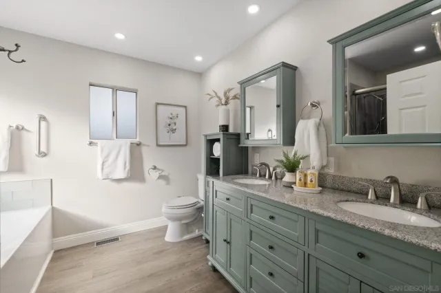 a spacious bathroom with double vanity a toilet a double vanity and a mirror