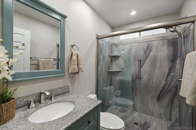 a bathroom with a granite countertop sink toilet and shower