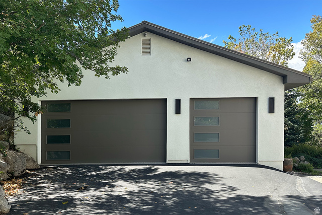 11454 South Oberland Road Sandy, UT 84092 - Photo 81 of 103 Stucco exterior featuring dual garage doors with frosted glass panels, an asphalt driveway, and exterior lighting fixtures