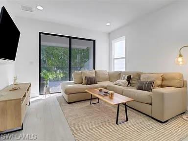 9011 Madrid Circle Naples, FL 34104 - Photo 12 of 20 a living room with furniture a flat screen tv and a large window