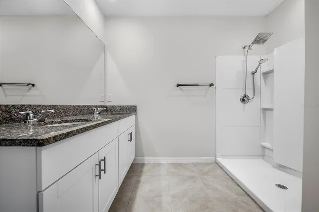 a bathroom with a granite countertop sink a toilet and shower