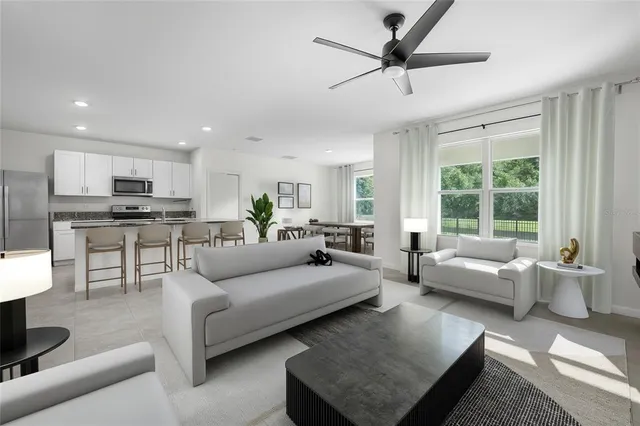 a living room with furniture and a large window with kitchen view