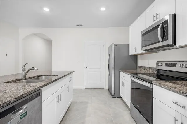 a kitchen with granite countertop cabinets stainless steel appliances and a counter space