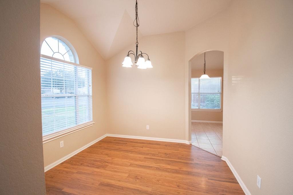 312 Pheasant Ridge Drive Round Rock, TX 78665 - Photo 12 of 34 Natural light pours into this dining space, highlighting the warm wood flooring and elegant arched window.