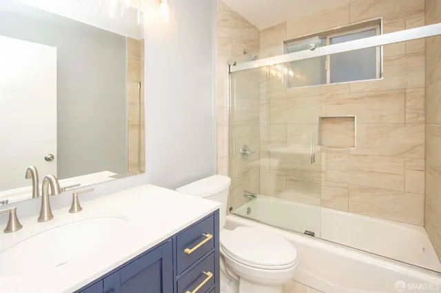 a bathroom with a granite countertop sink a toilet and shower