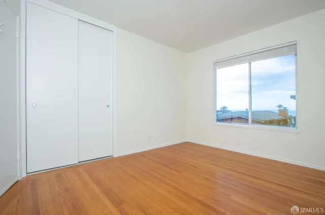 a view of a big room with wooden floor and windows