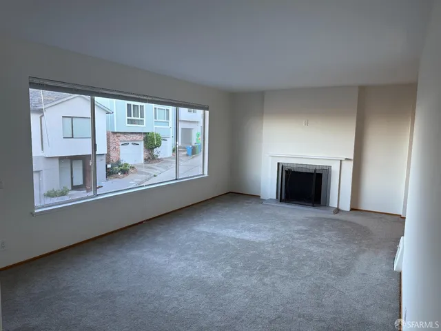 a view of an empty room with a fireplace and a window