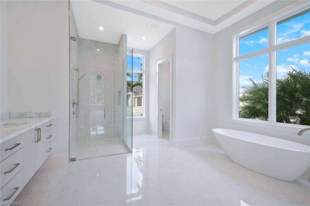 16743 Enclave Circle Naples, FL 34110 - Photo 15 of 42 a bathroom with a granite countertop sink a toilet and shower