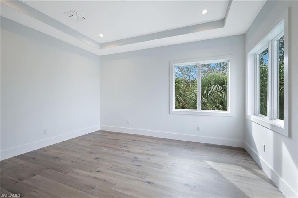 16743 Enclave Circle Naples, FL 34110 - Photo 20 of 42 an empty room with wooden floor and windows