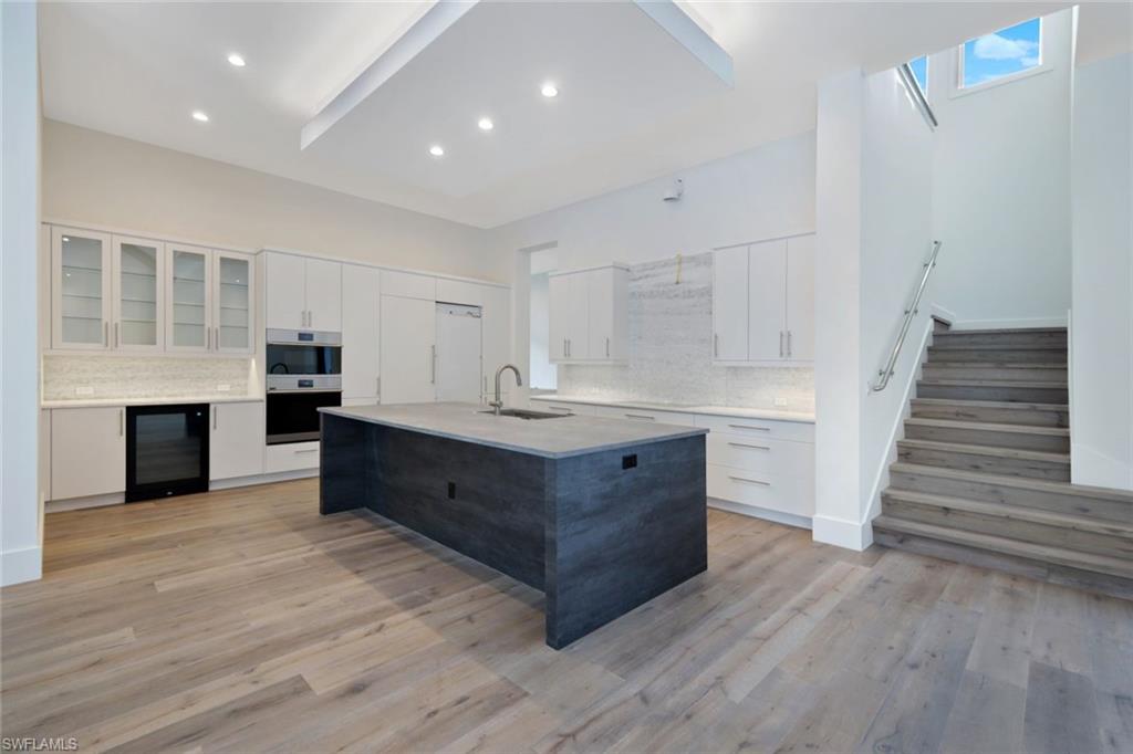 16743 Enclave Circle Naples, FL 34110 - Photo 10 of 42 a kitchen with stainless steel appliances kitchen island wooden floors and cabinets